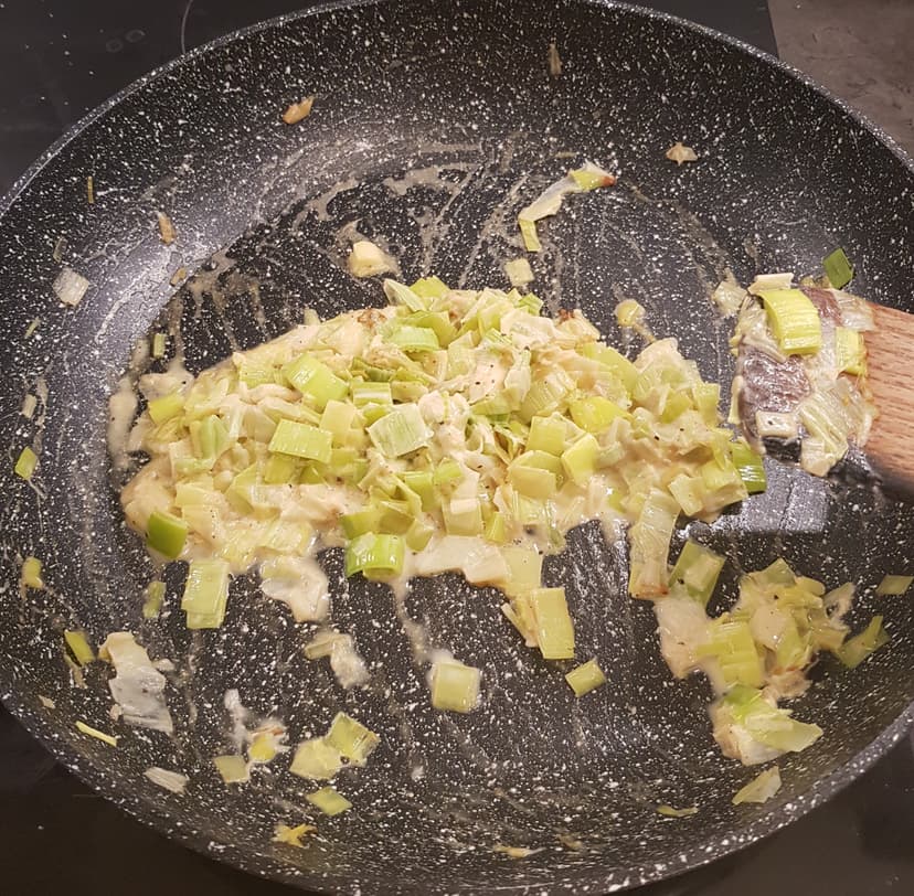 Fondu de poireaux dans une poêle avec de la crème et l'assaisonnement 