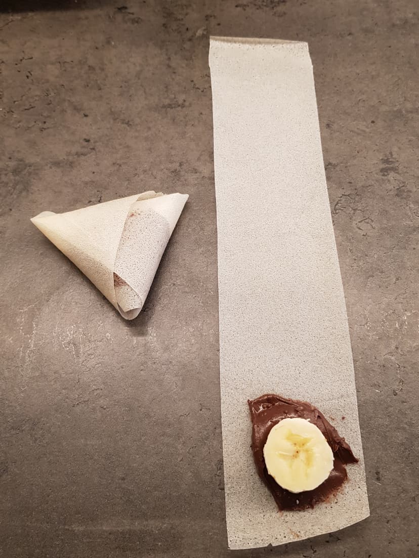 Banane, pâte à tartiner sur un morceau de feuille de brick et une brick plié en forme de samoussa